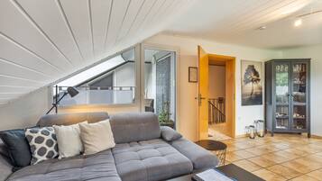 Ein modernes Wohnzimmer mit einem grauen Ecksofa, einem Couchtisch und einer Fernbedienung.