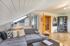 Un salon moderne avec un canapé d’angle gris, une table basse et une télécommande.