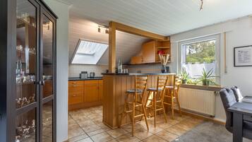 Eine Küche mit Holzausstattung, einer Bar mit Hockern, einem Oberlicht und einem Fenster mit Pflanzen.