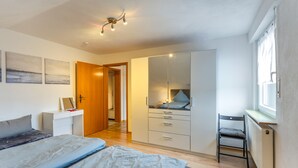 Een slaapkamer met een bed, een kledingkast, een bureau en een stoel.