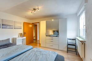 Ein Schlafzimmer mit Bett, Kleiderschrank, Schreibtisch und Stuhl.