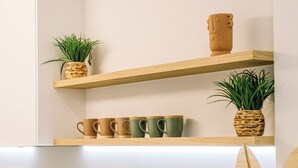 Een keuken met houten planken waarop mokken, een ananas en een mand met fruit staan.