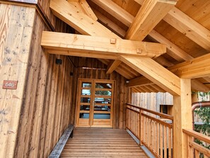 Un bâtiment en bois avec un escalier en bois menant à une porte dotée de panneaux de verre.