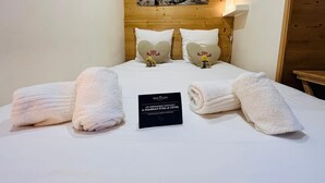 Una habitación de hotel con una cama, dos almohadas con forma de corazón, un cartel y un cuadro colgado en la pared.