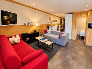 Ein modernes Wohnzimmer mit einem roten Sofa, einem grauen Sofa und einem flachbildfernseher an der Wand.