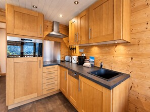 A modern kitchen with wooden cabinetry, stainless steel appliances, and a black countertop.