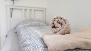 Uma cama com um cobertor enrolado e um edredom estampado.