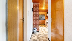 Um corredor com portas de madeira, parede de tijolos, chão de azulejos e uma janela com vista.
