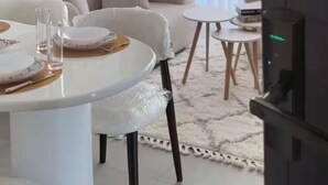 Un salón moderno con zona de comedor, que incluye una mesa redonda, sofás y arte abstracto en la pared.