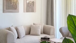 Una sala de estar moderna con un sofá color beige, una mesita redonda y una planta grande.