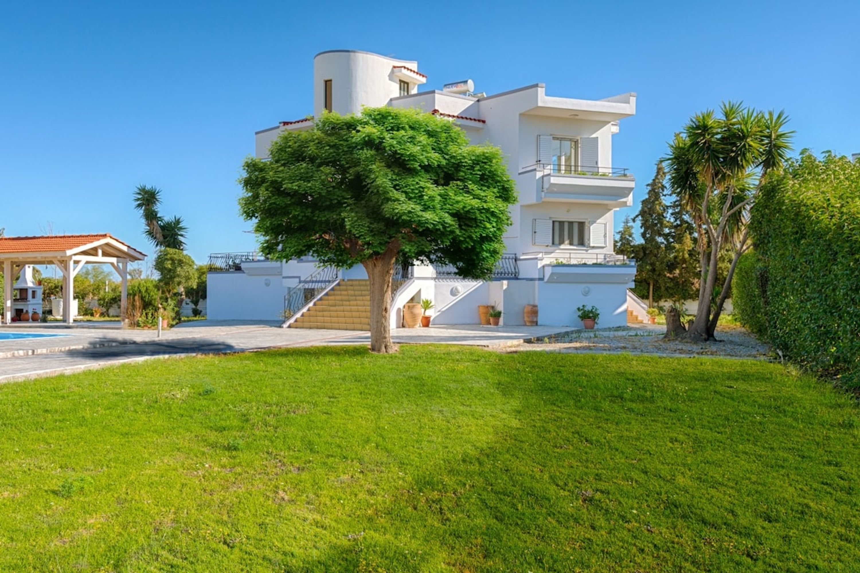 A modern two-story house with a flat roof, a covered patio, and a swimming pool.