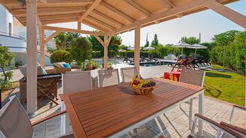 An outdoor patio with a wooden table, chairs, and a fruit basket.