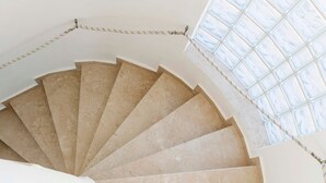 A spiral staircase with beige steps and white walls, leading to a skylight. - Villa Katherina - Tsambika View (Monastiri i Tsampika)