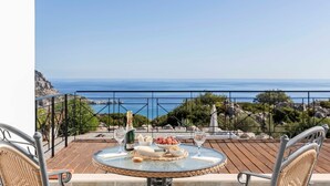 A round table with a glass top, surrounded by wicker chairs, set on a balcony overlooking the sea. - Villa Katherina - Tsambika View (Monastiri i Tsampika)