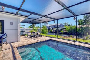 A covered outdoor swimming pool with lounge chairs, a patio area, and a view of neighboring houses. - Venice 3BR Canal Home | Heated Pool, Near Braves (Venice)