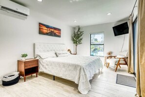 A bedroom with a bed, bedside table, and a window. - Venice 3BR Canal Home | Heated Pool, Near Braves (Venice)
