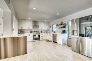 A modern kitchen with white cabinets, stainless steel appliances, and a wooden countertop. - Venice 3BR Canal Home | Heated Pool, Near Braves (Venice)