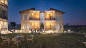 A two-story stone building with balconies, a central staircase, and outdoor seating. - Delight The Lavish Loft Corbett (Kaladhungi)