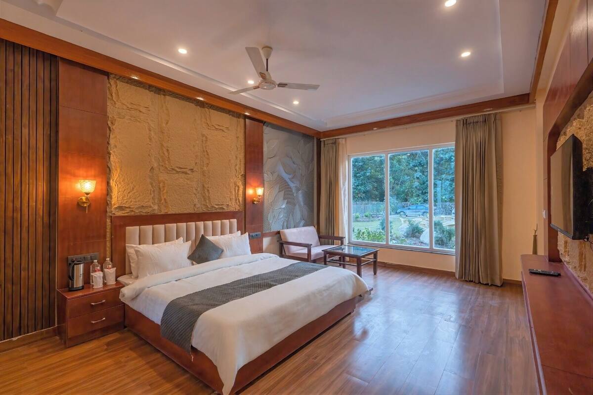 A spacious bedroom with a large bed, a ceiling fan, a seating area, and a view of the outdoors.