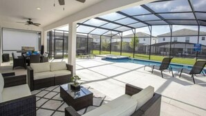 Ein großzügiger Patio-Bereich mit Glasveranda, Gartenmöbeln und einem Swimmingpool.