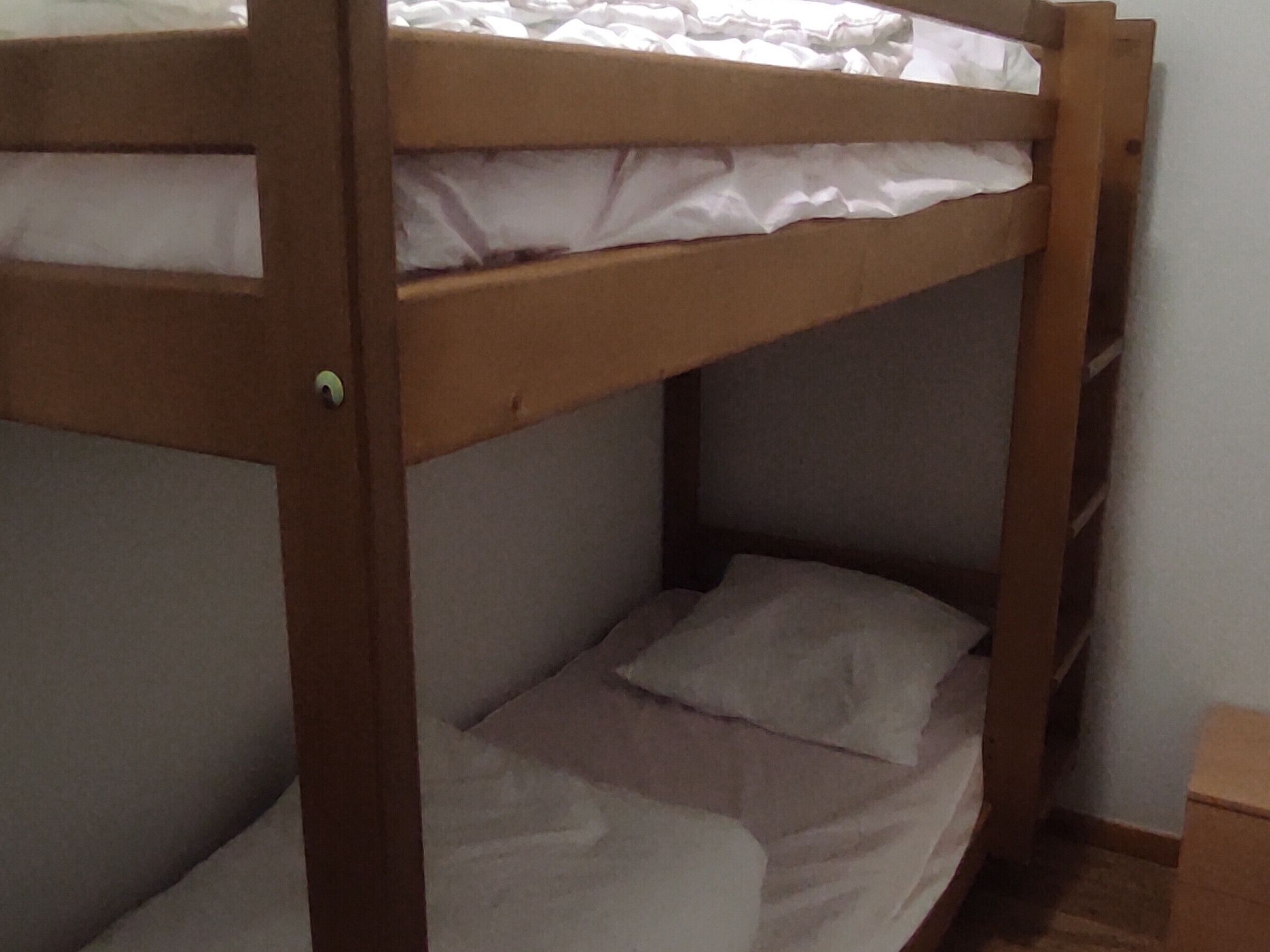 Un lit superposé avec une structure en bois et une literie blanche.