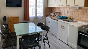 Kompakti keittiö, jossa on ruokapöytä, tuolit, kahvinkeitin ja astianpesukone.