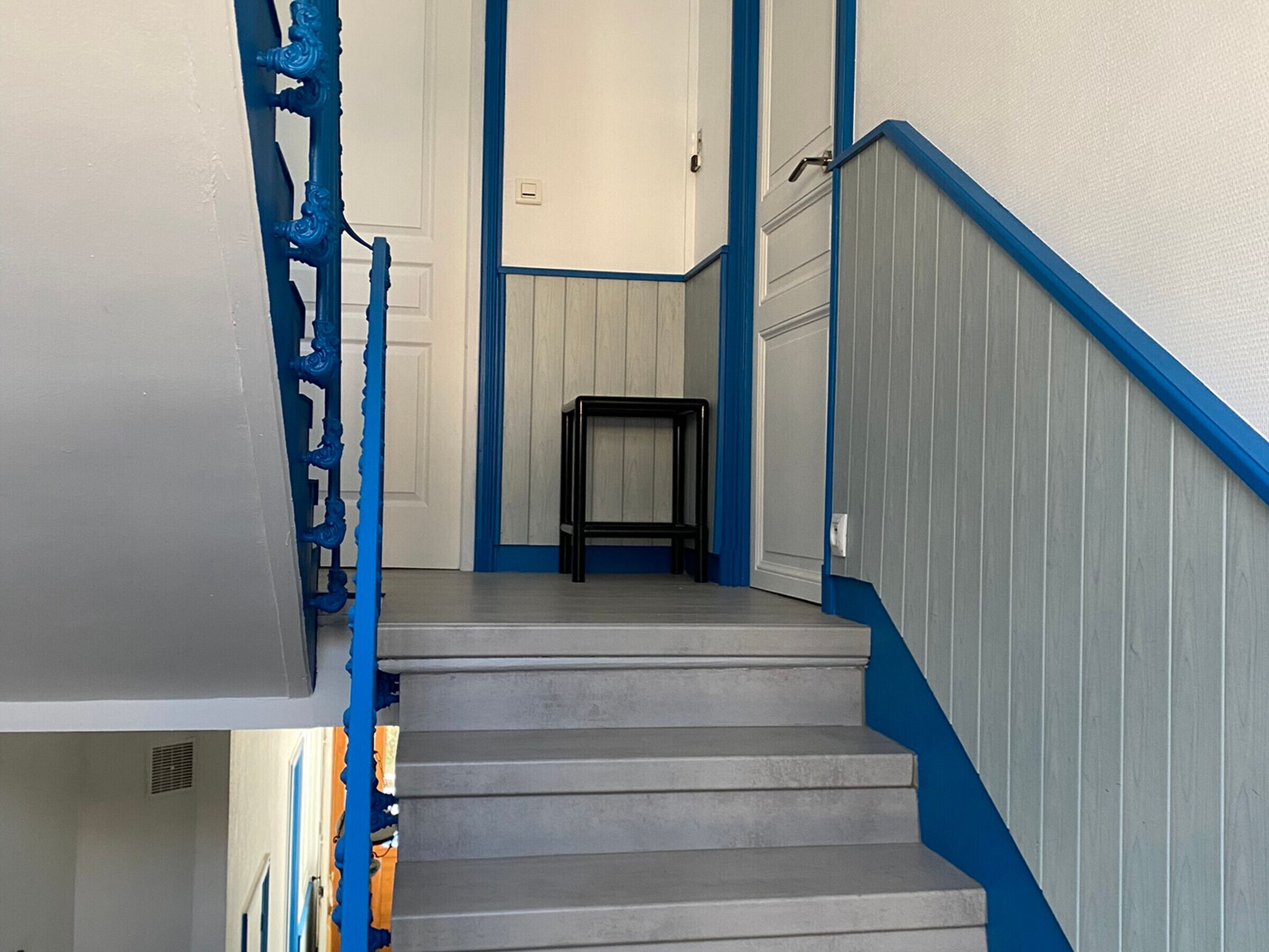 Eine Treppe mit blauer Zierleiste und einem kleinen Tisch oben.