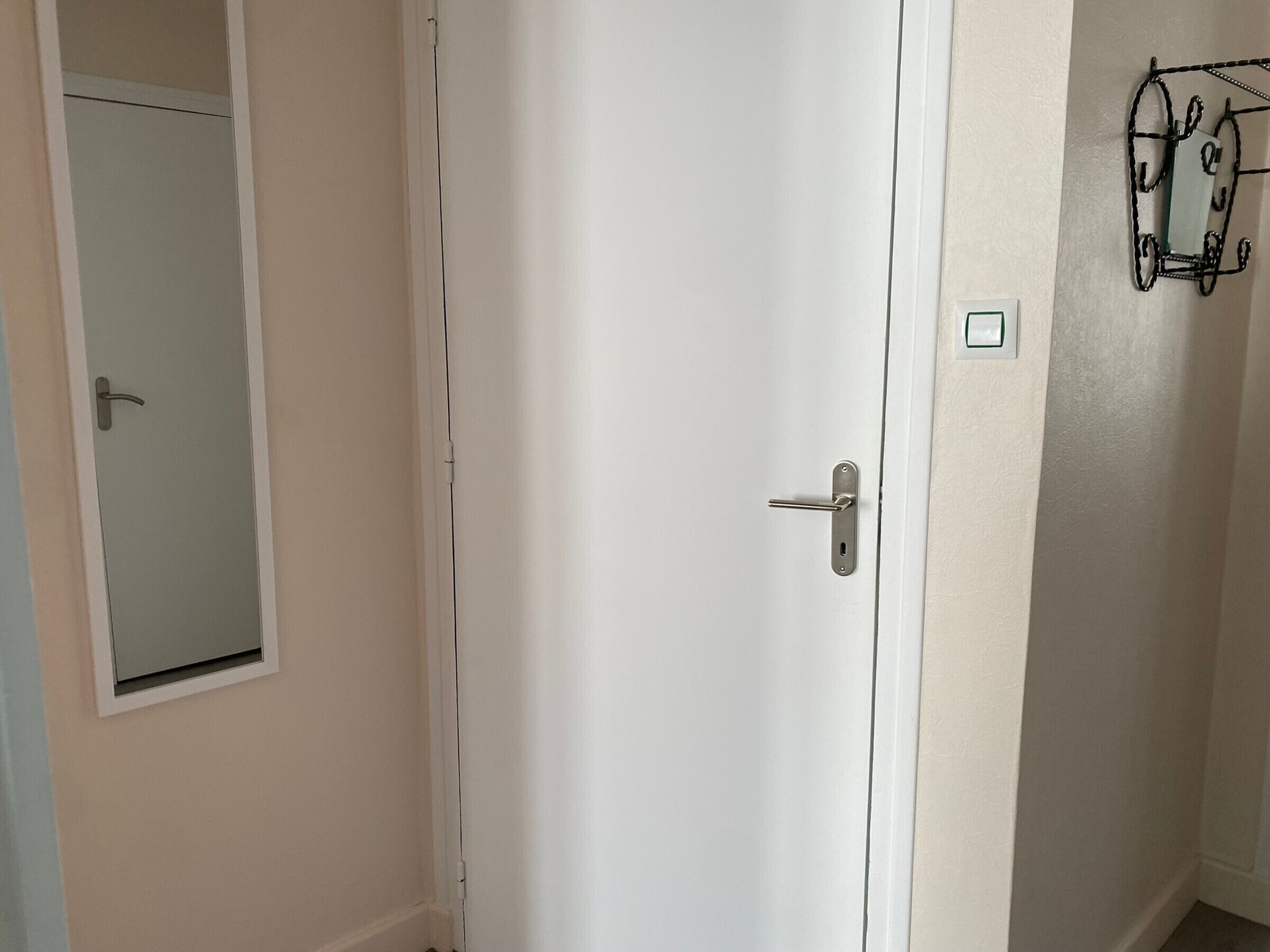 Una porta blanca amb un mànec platejat i una petita finestra rectangular a dalt.