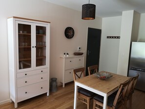 A compact kitchen with a wooden table, white cabinets, and a black clock on the wall. - 2-room apartment with garden and parking, near Spa and ski resort (Mont-Dore)
