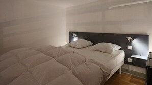 A bedroom with a bed, a headboard, bedside tables, and wall-mounted lights. - Bright city-center loft, near thermal baths, for 4 guests (La Bourboule)