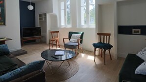 Ein geräumiges Wohnzimmer mit großem Fenster, Kamin und Fernseher.