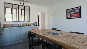 Eine moderne Küche mit einem Holzespeisetisch, Stühlen und einer Kücheninsel. An der Wand hängt ein gerahmtes Schild und über der Spüle befindet sich ein Fenster.