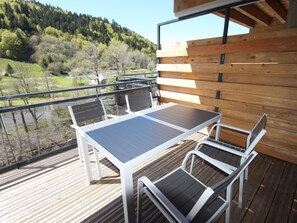 Eine Holzterrasse mit Tisch und Stühlen mit Blick auf eine bewaldete Landschaft.