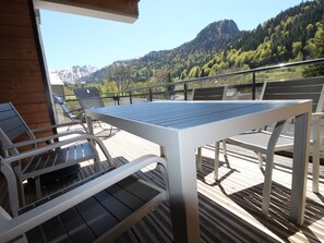 Eine Terrasse im Freien mit Tisch und Stühlen, mit Blick auf eine Berglandschaft.