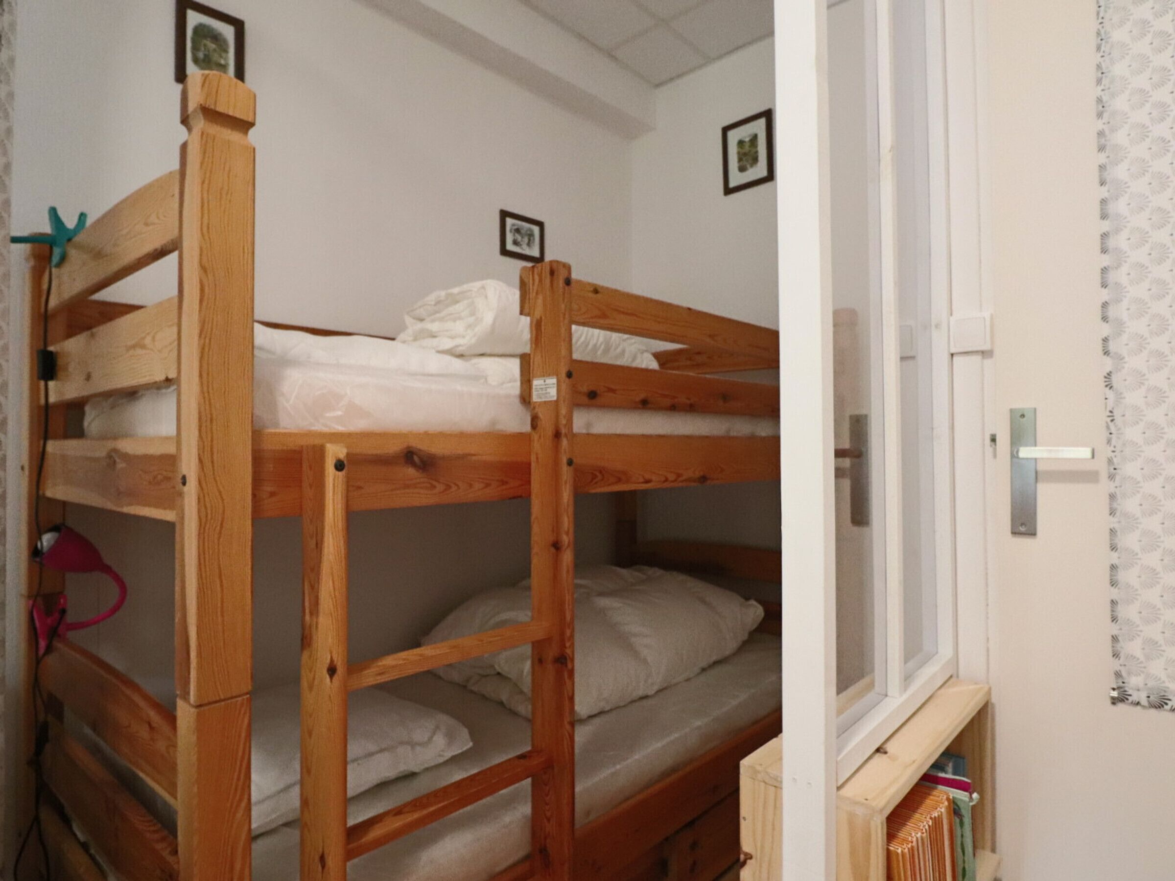 Une chambre avec un lit superposé, une porte et une fenêtre.