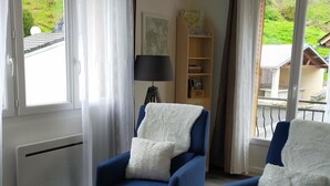 A room with two blue armchairs, a white radiator, a lamp, and a bookshelf. - L'R du Roc: 4* Duplex Apartment with Terrace and Garage (La Bourboule)