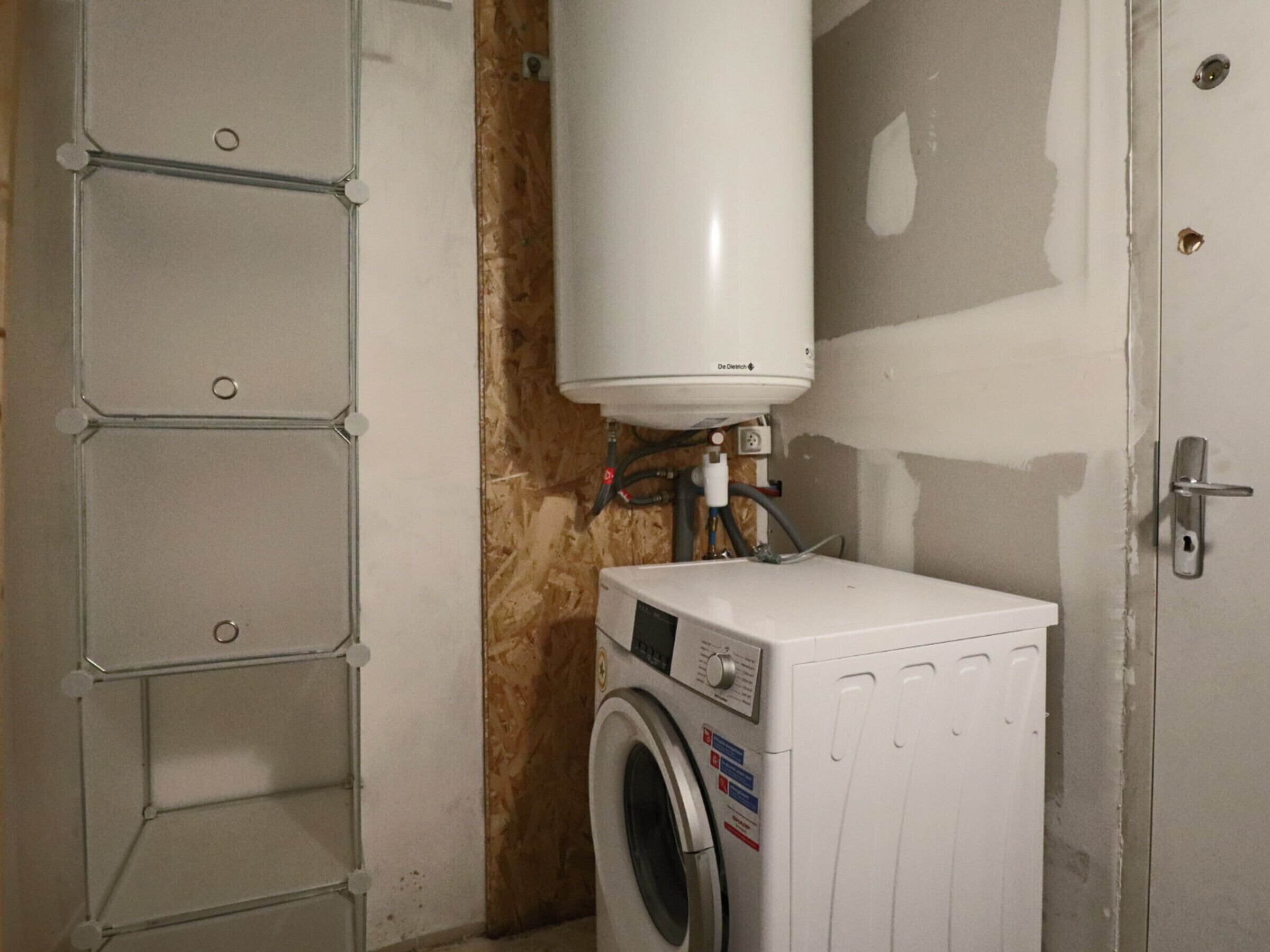 A laundry room with a washing machine and a water heater.