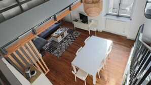 Un salon moderne avec un canapé, une table à manger et un luminaire suspendu.