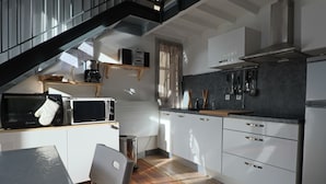 Une cuisine moderne avec des meubles blancs, un four à micro-ondes, un grille-pain et un évier en acier inoxydable.