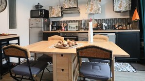 Een kleine keuken met een eettafel, stoelen en een magnetron.