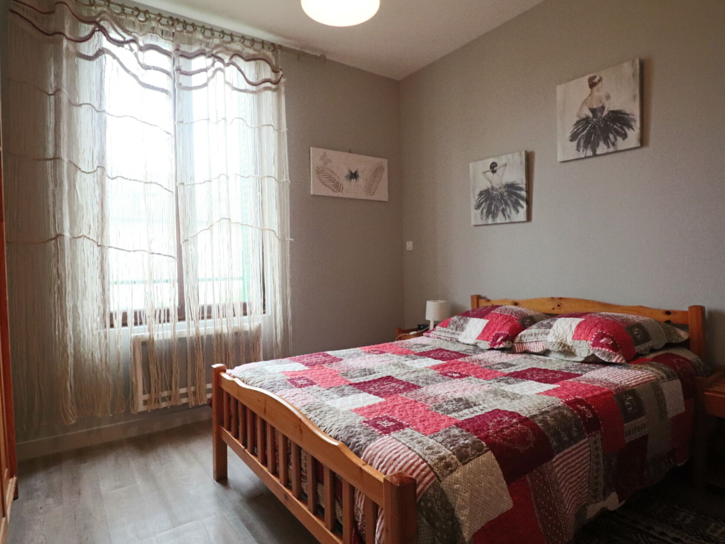 Camera da letto con un letto in legno, una coperta trapuntata, una finestra con tende e decorazioni alle pareti.