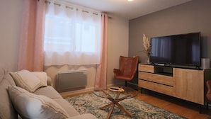 A modern living room with a sofa, a glass coffee table, a TV, and a wooden cabinet. - New 4* house in Mont Dore for 6 people (Mont-Dore)