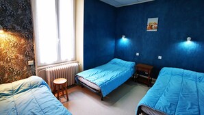Et værelse med to senge, en radiator, et vindue og en væg med blomstermønster.