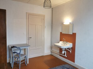 A small, compact room with a white door, a white sink with a mirror above it, and a small table with a chair. - Apartment for 6 in La Bourboule with WiFi (La Bourboule)