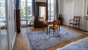 Una habitación de hotel con un escritorio de madera, dos sillas, un espejo grande y una alfombra estampada.