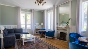Un salón amplio con un sofá grande, dos sillones azules, una mesa de centro y una chimenea.