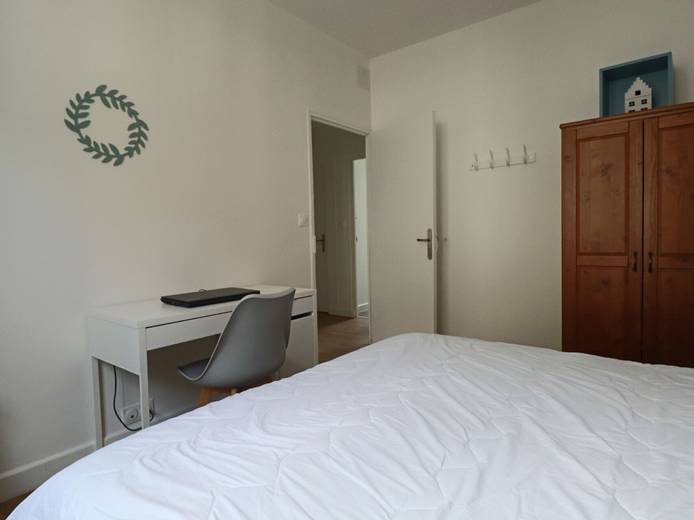 Une chambre à coucher avec un lit, un bureau et une chaise, une armoire et une porte.