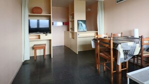 Een ruimtelijk ingerichte leefruimte met een eethoek, een televisie en een kleine tafel.