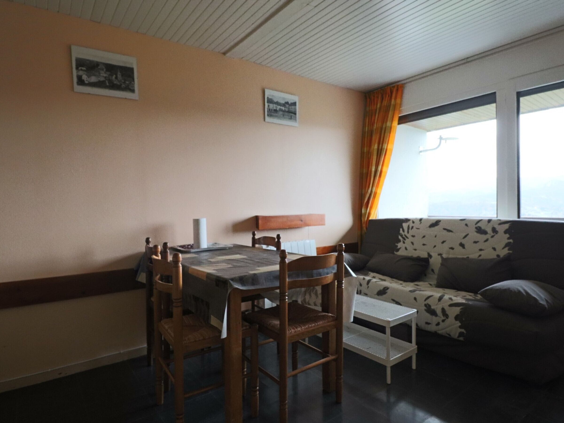 Un comedor con una mesa, sillas, un sofá y un ventanal con cortinas.