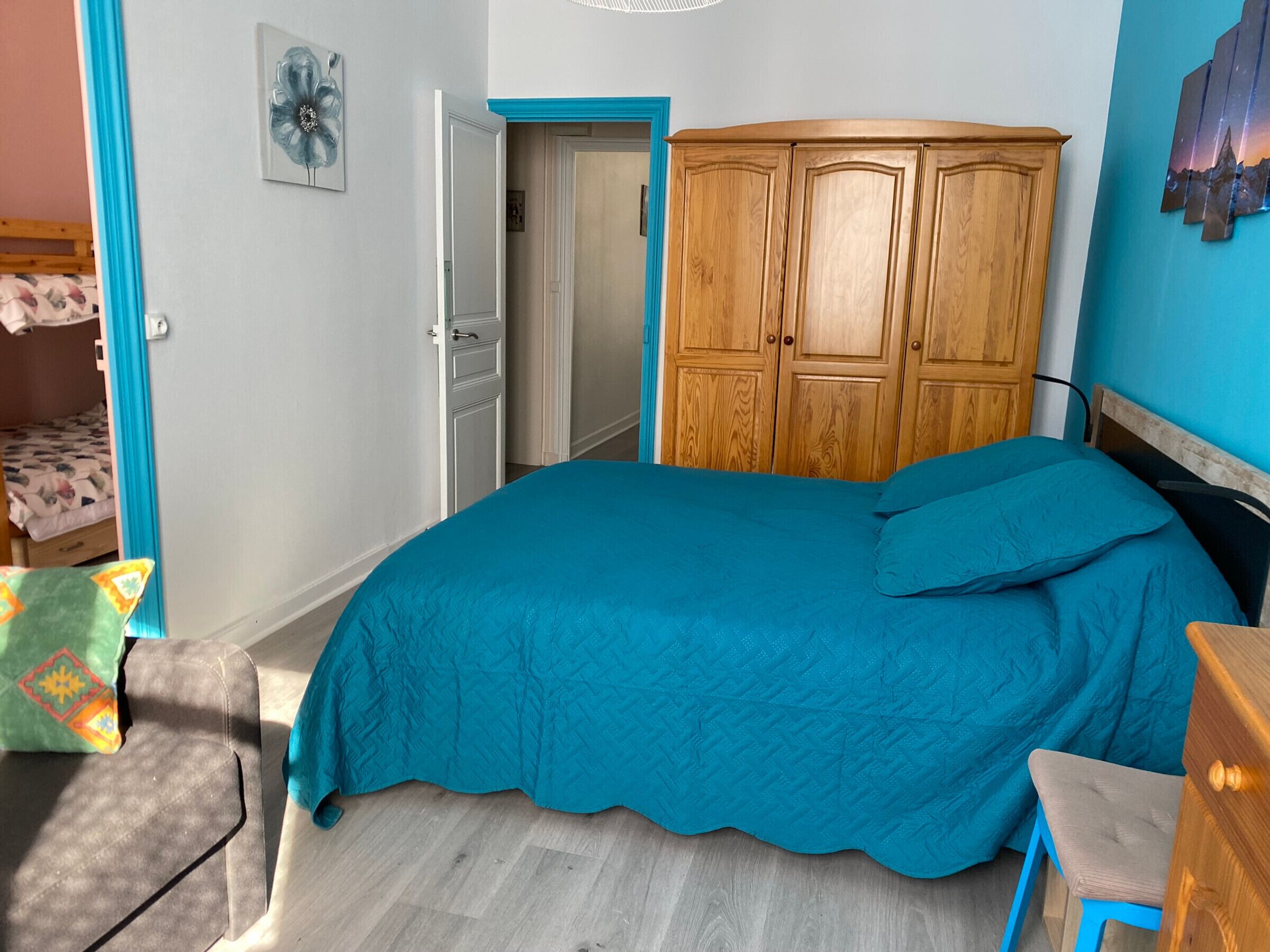 Ein Schlafzimmer mit einem Bett, einem Holzschrank, einem Schreibtisch und einem Stuhl.